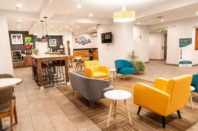 a waiting room with yellow chairs and tables at Quality Inn & Suites Oakwood Village - Cleveland South in Oakwood
