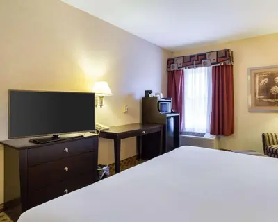 a hotel room with a bed and a flat screen tv at Quality Inn & Suites Oakwood Village - Cleveland South in Oakwood