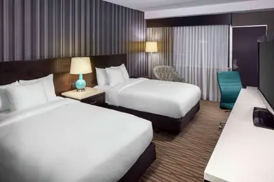 a hotel room with two beds and a chair at Wyndham Garden Westlake in Westlake