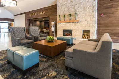 a lobby with a couch and chairs and a fireplace at Wyndham Garden Westlake in Westlake