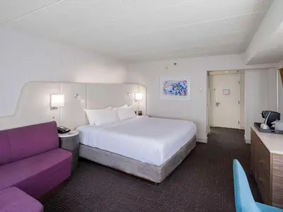 a hotel room with a bed and a purple couch at Sonesta Columbus Downtown in Columbus