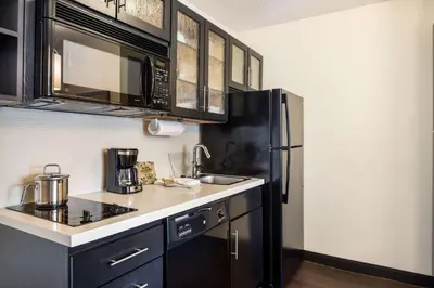a kitchen with black cabinets and a black refrigerator at Sonesta Simply Suites Columbus Airport Gahanna in Gahanna