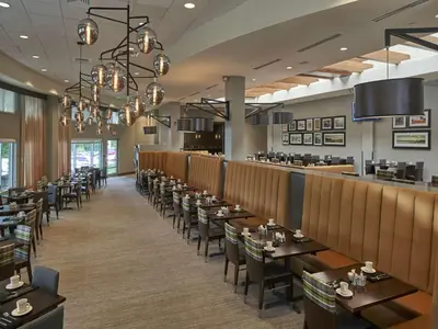 a dining room with tables and chairs and a bar at Hilton Cincinnati Airport in Florence