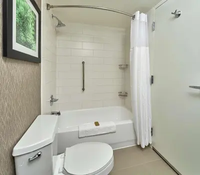 a white bathroom with a toilet and a tub and a shower at Hilton Cincinnati Airport in Florence