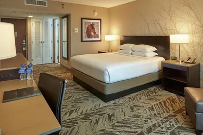 a hotel room with a large bed and a couch at Hilton Cincinnati Airport in Florence