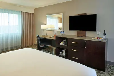 a hotel room with a bed and a desk with a television at Hilton Cincinnati Airport in Florence