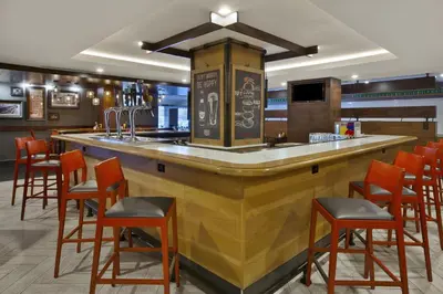 a bar in a restaurant with orange bar stools at Holiday Inn Columbus Dwtn-Capitol Square by IHG in Columbus