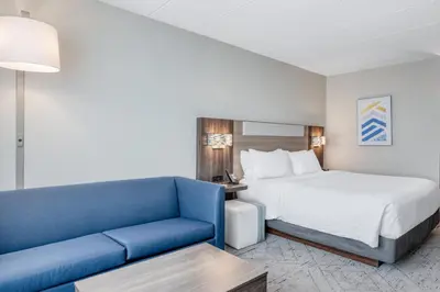 a hotel room with a bed and a blue couch at Holiday Inn Express Hotel & Suites Columbus Airport by IHG in Gahanna