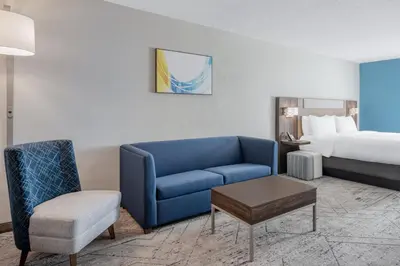a hotel room with a blue couch and a bed at Holiday Inn Express Hotel & Suites Columbus Airport by IHG in Gahanna