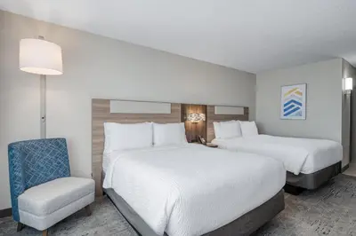 a hotel room with two beds and a chair at Holiday Inn Express Hotel & Suites Columbus Airport by IHG in Gahanna