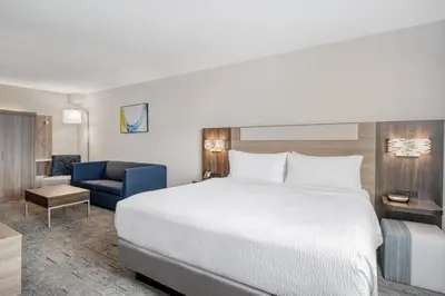 a hotel room with a bed and a blue chair at Holiday Inn Express Hotel & Suites Columbus Airport by IHG in Gahanna