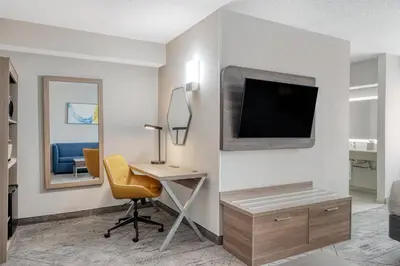 a room with a desk and a tv on a wall at Holiday Inn Express Hotel & Suites Columbus Airport by IHG in Gahanna