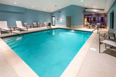 a pool in a hotel with chairs and tables at Holiday Inn Express & Suites Wadsworth by IHG in Wadsworth