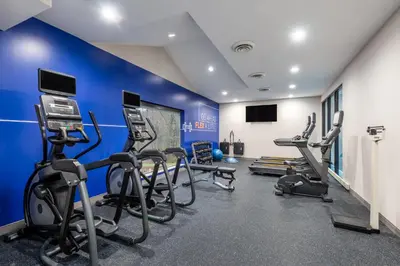a gym with cardio machines and a blue wall at Holiday Inn Express & Suites Wadsworth by IHG in Wadsworth