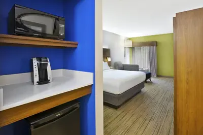 a hotel room with a bed and a tv on a shelf at Holiday Inn Express Hotel & Suites Cincinnati Northeast-Milford by IHG in Milford