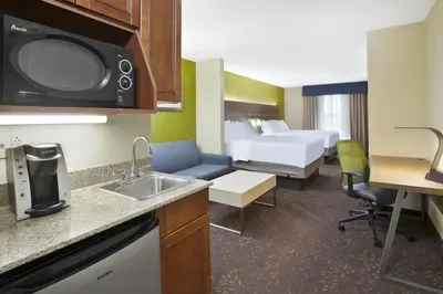a hotel room with a bed and a kitchen with a sink at Holiday Inn Express Hotel & Suites Circleville by IHG in Circleville