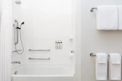 a white bathroom with a shower and a tub and towels at Holiday Inn Express Hotel & Suites Grove City by IHG in Grove City