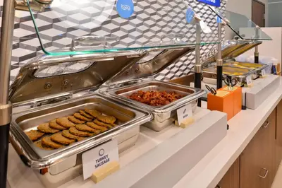 a buffet line with trays of food on a counter at Holiday Inn Express Hotel & Suites Grove City by IHG in Grove City
