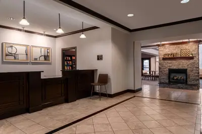 a lobby with a fireplace and a table and chairs at Staybridge Suites Akron-Stow-Cuyahoga Falls by IHG in Stow