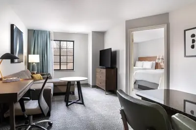 a hotel room with a desk and a room with a bed at Staybridge Suites Akron-Stow-Cuyahoga Falls by IHG in Stow