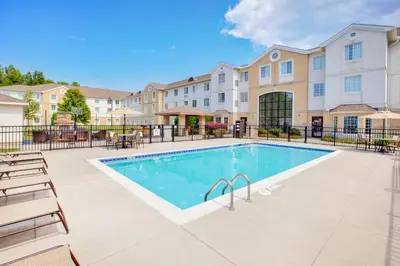 a swimming pool with chairs and a building at Staybridge Suites Cleveland Mayfield Heights Beachwood by IHG in Mayfield Heights