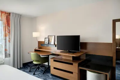 a hotel room with a desk with a television at Fairfield Inn & Suites by Marriott Cincinnati Uptown/University Area in Cincinnati
