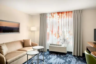 a living room with a couch and tables in front of a window at Fairfield Inn & Suites by Marriott Cincinnati Uptown/University Area in Cincinnati