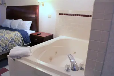 a bathroom with a bath tub and a bed at Americas Best Value Inn of Decatur in Decatur