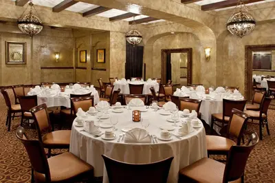 a dining room with white tables and chairs and chandeliers at Crowne Plaza Cleveland Airport by IHG in Middleburg Heights