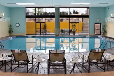 a pool with chairs and tables in a building at Crowne Plaza Cleveland Airport by IHG in Middleburg Heights