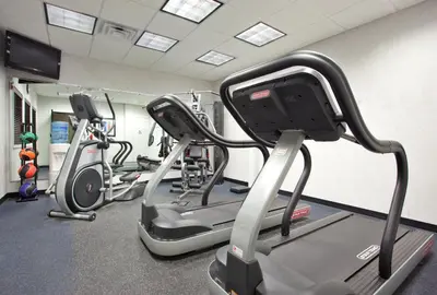 a gym with three treadmills and cardio machines at Holiday Inn Express Hotel and Suites Akron South-Airport Area by IHG in Akron