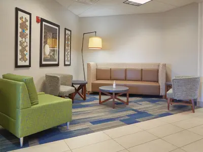 a waiting room with a couch and chairs and tables at Holiday Inn Express Hotel and Suites Akron South-Airport Area by IHG in Akron
