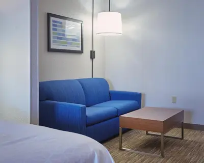 a living room with a blue couch and a table at Holiday Inn Express Hotel and Suites Akron South-Airport Area by IHG in Akron