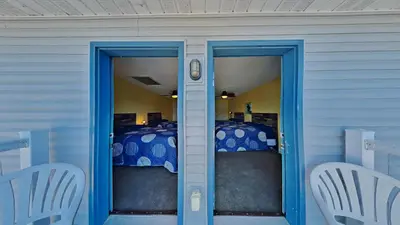 a room with a bed with blue doors and chairs at Put-in-Bay Waterfront Condo #205 in Put-in-Bay