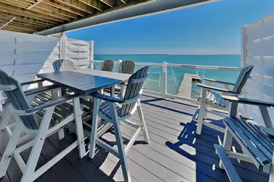 a table and chairs on a deck with the ocean at Put-in-Bay Waterfront Condo #205 in Put-in-Bay