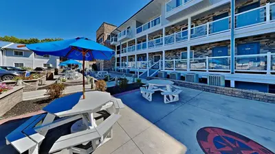 a patio with two chairs and a blue umbrella at Put-in-Bay Waterfront Condo #205 in Put-in-Bay