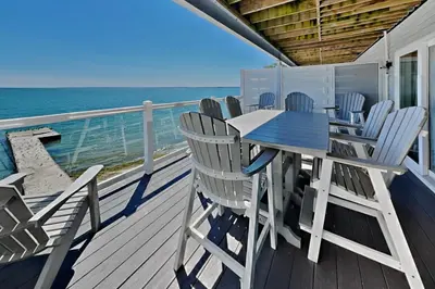 a deck with chairs and a table and the ocean at Put-in-Bay Waterfront Condo #205 in Put-in-Bay