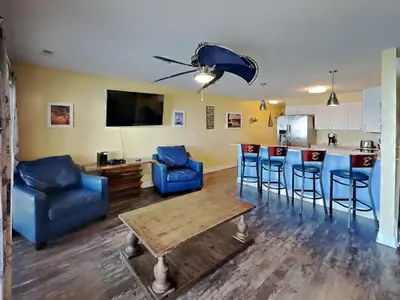 a living room with blue chairs and a kitchen at Put-in-Bay Waterfront Condo #211 in Put-in-Bay