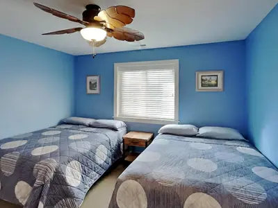 a blue bedroom with two beds and a ceiling fan at Put-in-Bay Waterfront Condo #211 in Put-in-Bay