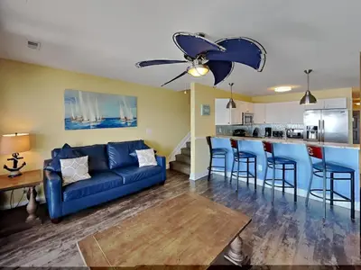 a living room with a blue couch and a kitchen at Put-in-Bay Waterfront Condo #202 in Put-in-Bay