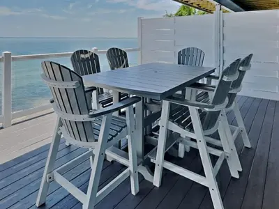 a wooden table and chairs on a deck with the ocean at Put-in-Bay Waterfront Condo #104 in Put-in-Bay