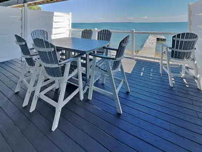 a table and chairs on a deck with the ocean at Put-in-Bay Waterfront Condo #105 in Put-in-Bay