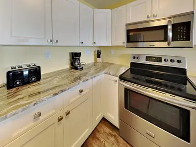 a kitchen with white cabinets and stainless steel appliances at Put-in-Bay Waterfront Condo #105 in Put-in-Bay