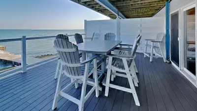 a table and chairs on a deck overlooking the ocean at Put-in-Bay Waterfront Condo #106 in Put-in-Bay