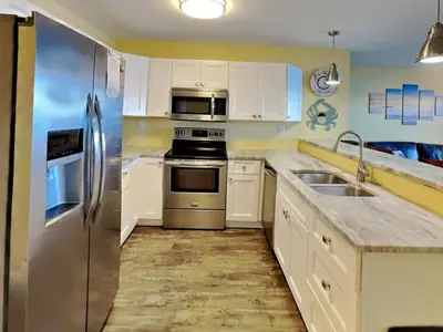 a kitchen with white cabinets and a stainless steel refrigerator at Put-in-Bay Waterfront Condo #111 in Put-in-Bay