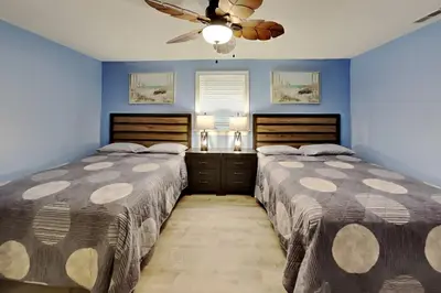 two beds in a bedroom with blue walls and a ceiling fan at Put-in-Bay Waterfront Condo #111 in Put-in-Bay
