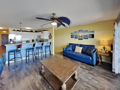 a living room with a blue couch and a kitchen at Put-in-Bay Waterfront Condo #113 in Put-in-Bay