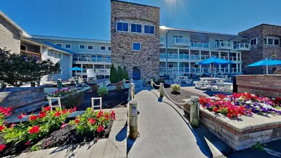 a walkway leading to a resort with flowers and umbrellas at Put-in-Bay Waterfront Condo #113 in Put-in-Bay