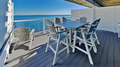 a table and chairs on a deck with the ocean at Put-in-Bay Waterfront Condo #113 in Put-in-Bay