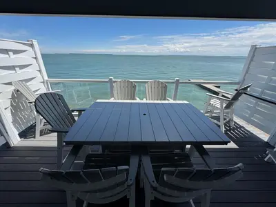 a blue table and chairs on a deck with the ocean at Put-in-Bay Waterfront Condo #209 in Put-in-Bay